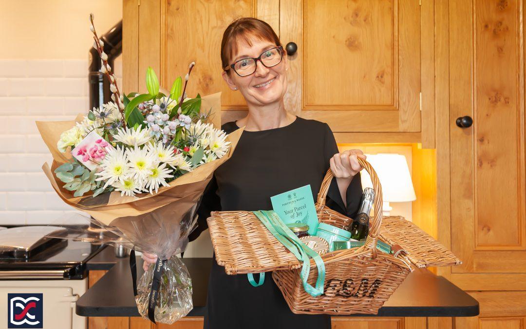 Christmas Comes Early. Natasha Cosby of David Cosby Estate Agents holding a beautiful bouquet of flowers and a delicious hamper.