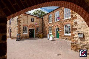 Towcester museum with blue skies - viewed through the stone and brick archway of a former Georgian Coaching Inn.