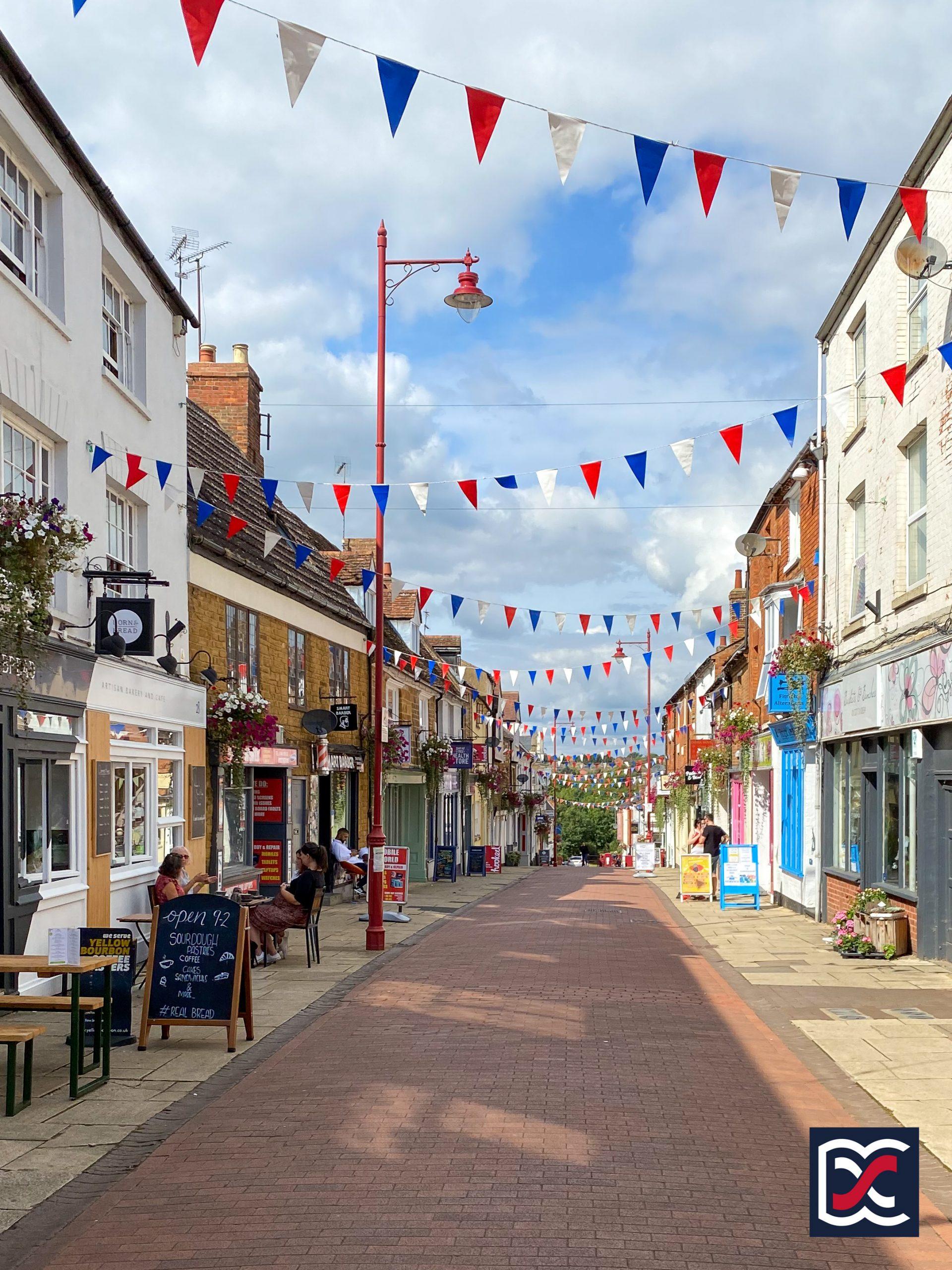 Sheaf Street, Daventry on a sunny day with bunting and outdoor café seating